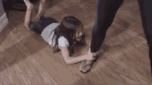 a woman is laying on the floor with her legs crossed while a person kicks her .