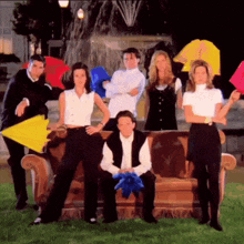 a group of friends posing for a picture with umbrellas in front of a fountain