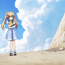 a girl in a blue dress is standing on a hill holding a book