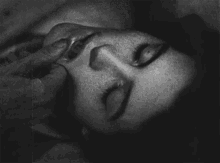 a black and white photo of a woman 's face with her eyes closed