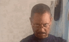 a man with glasses and a beard is making a funny face in front of a mirror .