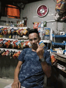 a man giving a thumbs up in front of a shelf full of snacks and a clock with the number 12 on it