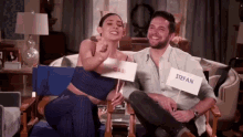 a man and a woman sitting next to each other with a sign that says ' stefan ' on it