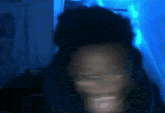 a blurry picture of a man 's face in a dark room with blue lights behind him .