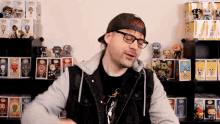 a man wearing glasses and a hat is standing in front of a display of funko pop figures