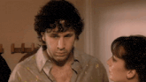 a man with curly hair looks at a woman