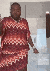 a man wearing a red and white dress is dancing in a bathroom .