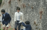 a group of people are standing next to each other in front of a wall .