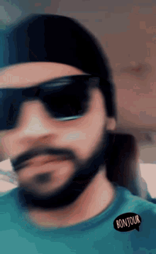 a blurry photo of a man wearing sunglasses and a bonjour sticker on his shirt