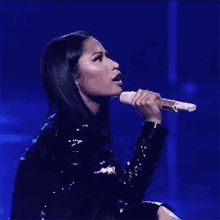 a woman in a black jacket is singing into a microphone .