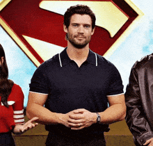 a man wearing a watch stands in front of a superman symbol