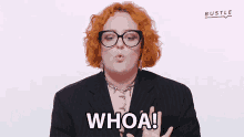 a woman with red hair wearing glasses and a black suit says whoa