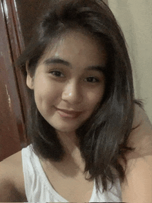 a woman wearing a white tank top is smiling for the camera