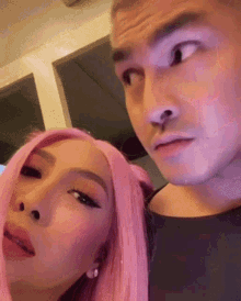 a man and a woman with pink hair are standing next to each other and making funny faces .