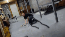 a man is playing with a rope in a basement with a yellow sign that says ' slippery when wet '