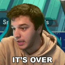 a man in a hoodie is sitting in front of a computer screen .