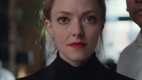 Amanda Seyfried as Elizabeth Holmes - black turtleneck, messy upsweep, unblinking eyes, red lipstick, green juice