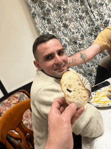 a man with a tattoo on his arm holds a piece of bread in front of his face