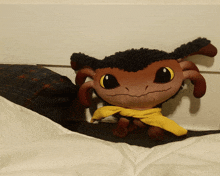 a stuffed animal with a yellow scarf around its neck is sitting on a bed