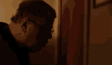 a man wearing glasses is looking through a door and the word ouvr is on the bottom