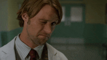 a man in a lab coat and tie says pretty much in white letters