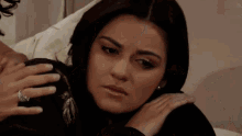 a woman with a ring on her finger is sitting on a bed