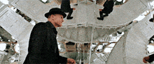 a man in a top hat is standing in front of a mirror looking at his reflection