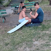a boy sits on a tire while another boy sits at a picnic table