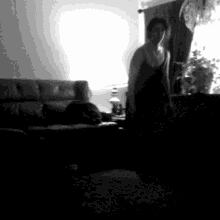 a woman is standing in a living room with a couch and a lamp