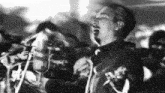 a man is singing into a microphone with a crowd behind him