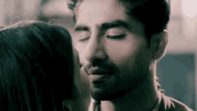 a man and a woman are kissing with their eyes closed in a close up of their faces .