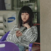 a young woman is sitting in a chair looking at her phone .