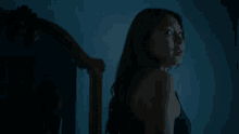 a woman in a black top stands in front of a blue wall