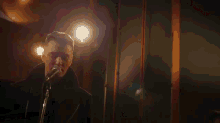 a man is singing into a microphone in a dark room in front of a light .