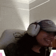 a woman wearing headphones and a hat is smiling in a room