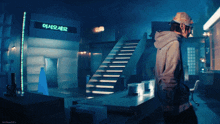 a man in a hoodie stands in front of a sign that says ' a ' on it
