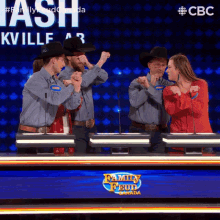 a group of people standing in front of a family feud board