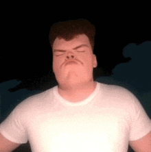 a man with a mustache is wearing a white t-shirt and making a funny face .