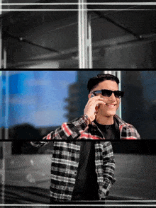 a man wearing sunglasses is smiling while talking on a cell phone