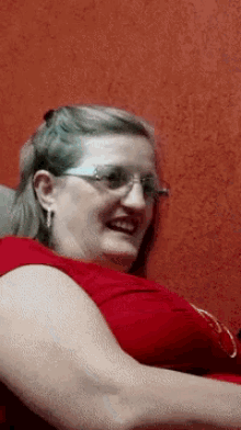 a woman wearing glasses and a red shirt smiles for the camera