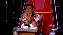 a man in a colorful jacket sits in a chair with the words cr media site below him