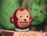 a stuffed monkey making a funny face while sitting on a box