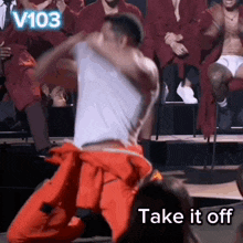 a man in a white shirt is dancing in front of a crowd with the words take it off in the corner