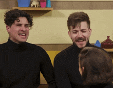 a man with a mustache is laughing while standing next to two other men