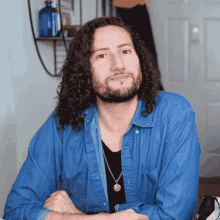 a man with long curly hair and a beard wearing a blue shirt