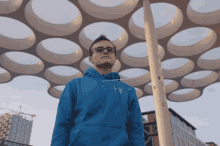 a man wearing glasses and a blue hoodie stands in front of a dome