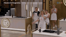 a group of people wearing aprons with the letter m on them are standing in a kitchen