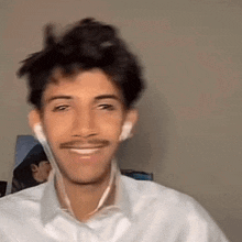 a man with a mustache and ear buds is smiling .