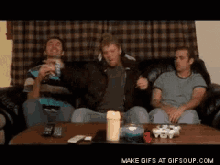 a group of men are sitting on a couch with a candle on a table