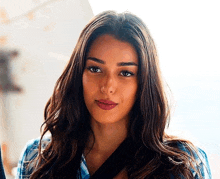 a woman with long brown hair is wearing a blue shirt